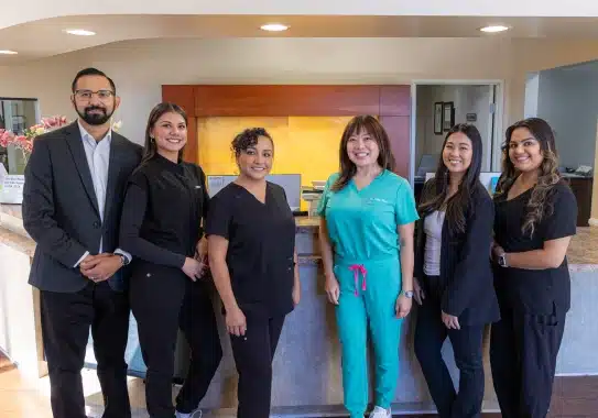 Dental team members standing together in modern office hallway at Kelly Smile Dentistry Victorville.