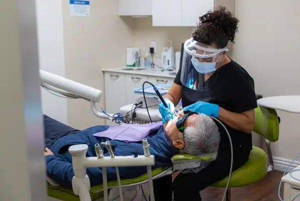 Dentist in mask treating patient in dental chair at Kelly Smile Dentistry Victorville clinic.