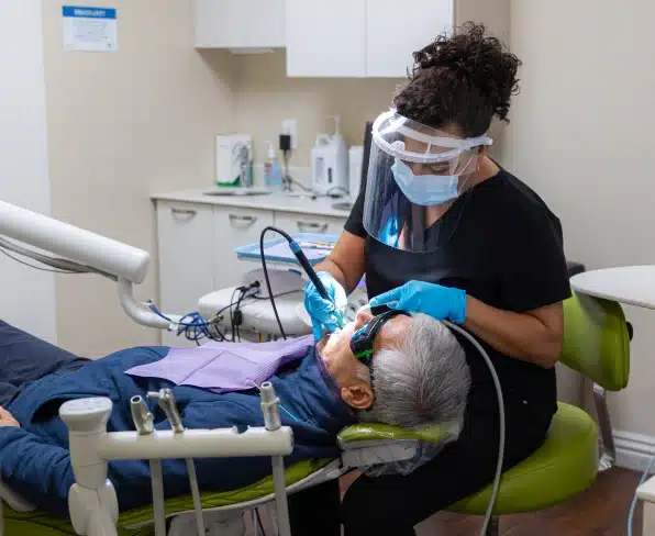 Dentist in mask and gloves treating patient in dental chair at Kelly Smile Dentistry Victorville clinic.